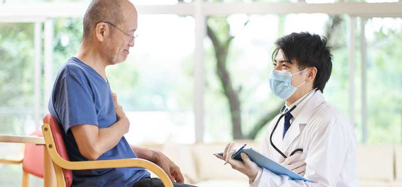Caregiver kneeling in front of a patient sitting in a chair.