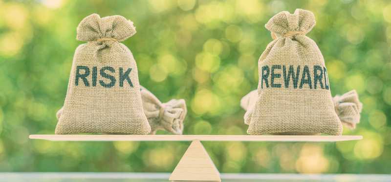 Burlap bags saying Risk and Reward sitting on a balance.
