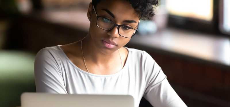 Woman in glasses is looking at laptop.