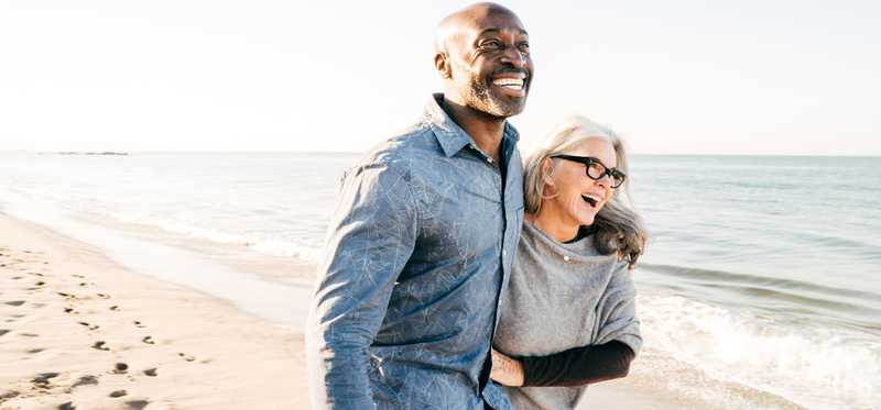Laughing people arm in arm on the beach.