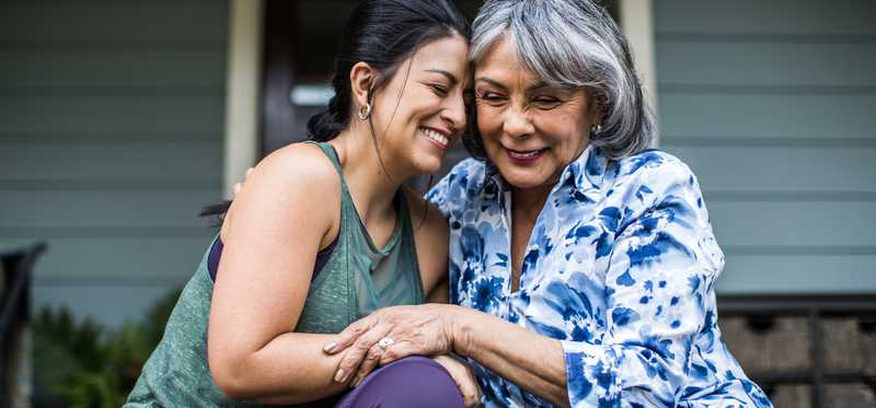 Two people embrace while seated on the stoop of a house.