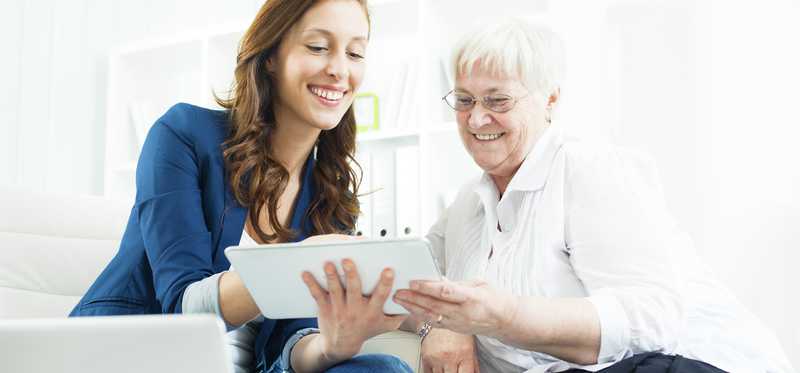 Two people smiling while looking at tablet.