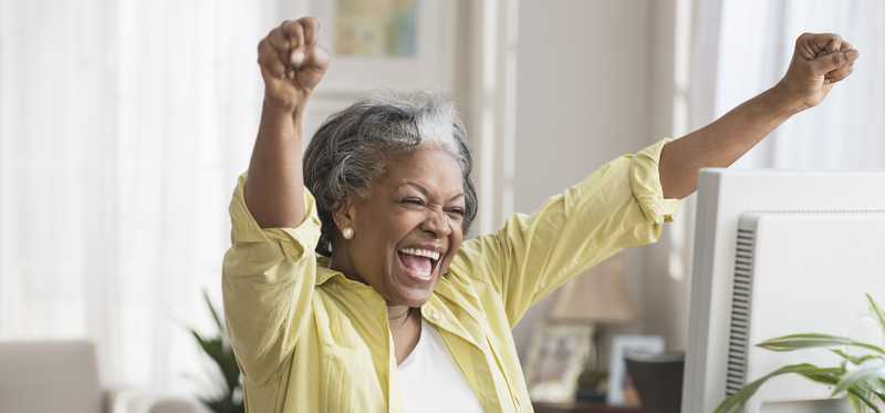 Person at desk is celebrating with hands in the air.