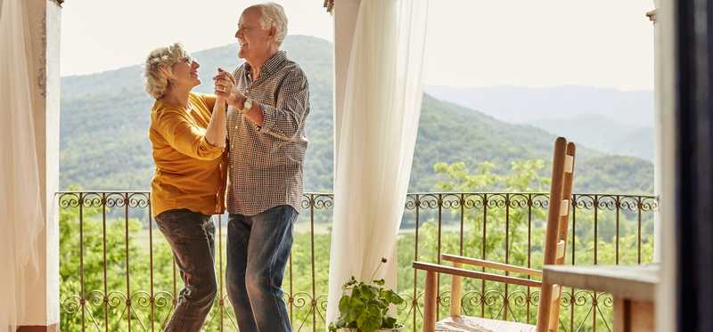 Two people dancing on patio overlooking mountainside.