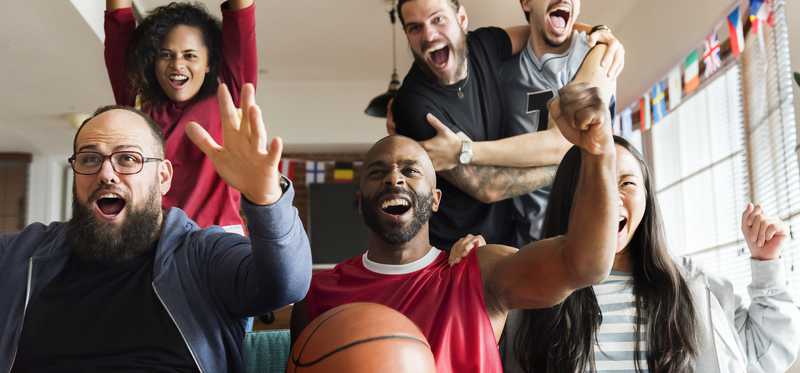Friends watching sports and cheering excitedly.