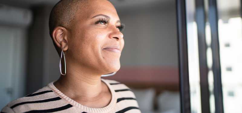 Close-up of adult looking empowered while smiling near window.
