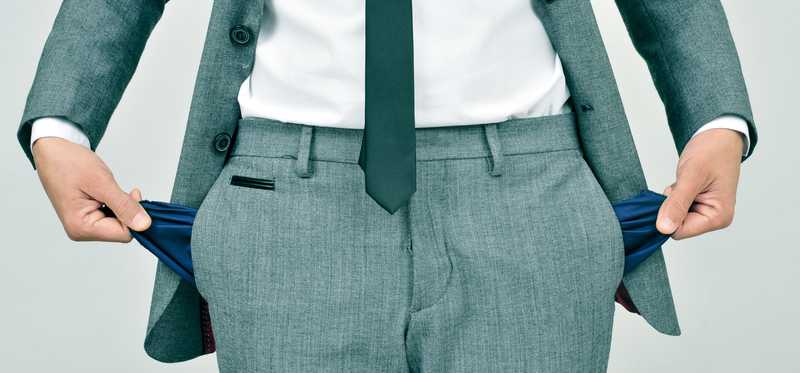 Person in suit turning out pockets to show they're empty.