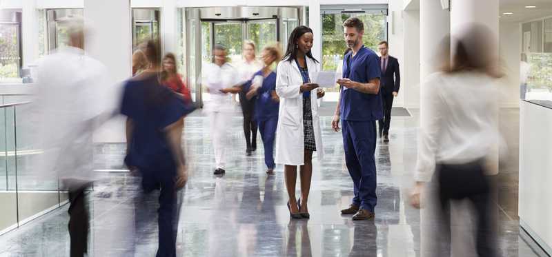 People walking in lobby of a hospital or large lab building.