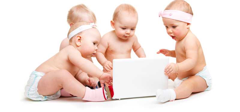 Quadruplet infants playing with an item on the ground.