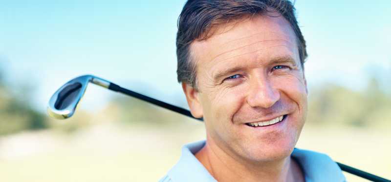 Person smiling with a golf club.
