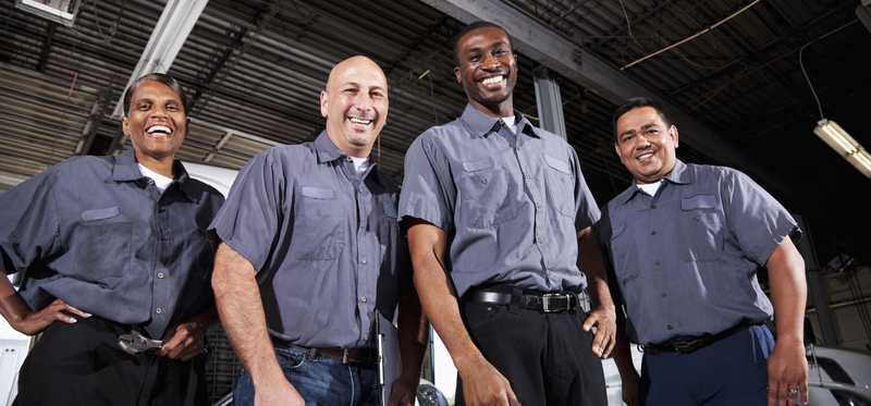 A group of people wearing the same work clothes and standing in a factory.