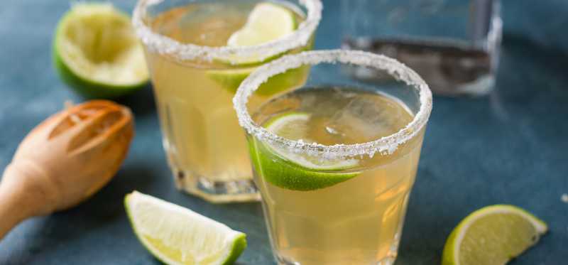 Two margaritas on the rocks with lime.