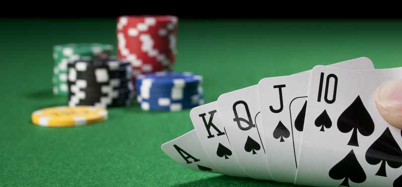 Poker hand showing a royal flush on a poker table with chips in background.