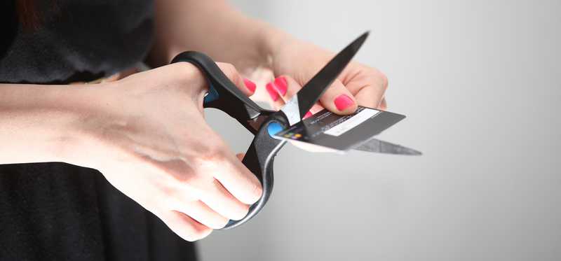 Hands cutting credit card with scissors.