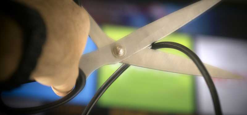 Scissors cutting cable in front of TV