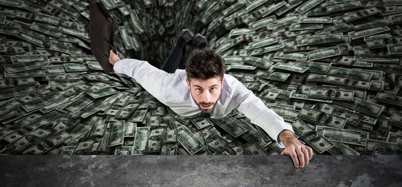 A man is being pulled into a pit of money.