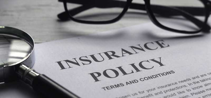 Piece of paper saying Insurance Policy with a pair of glasses atop it.