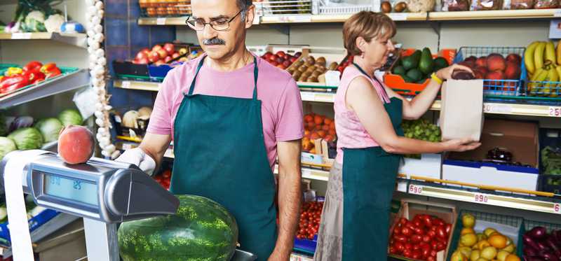 Middle aged man weighing produce at his job.