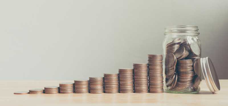 Coins arranged in growing stacks next to a jar full of them.