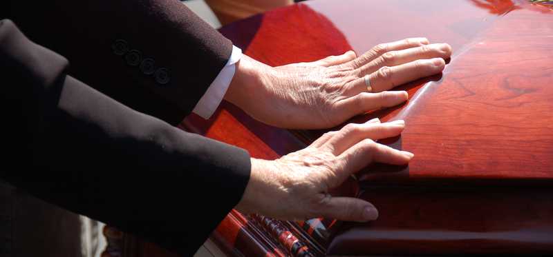 Hands on top of a casket.