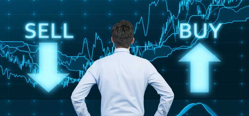 A man is looking at the words buy and sell, with his hands on his hips, as if deciding.