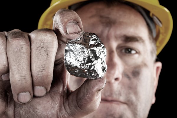 Miner holding up a silver nugget.