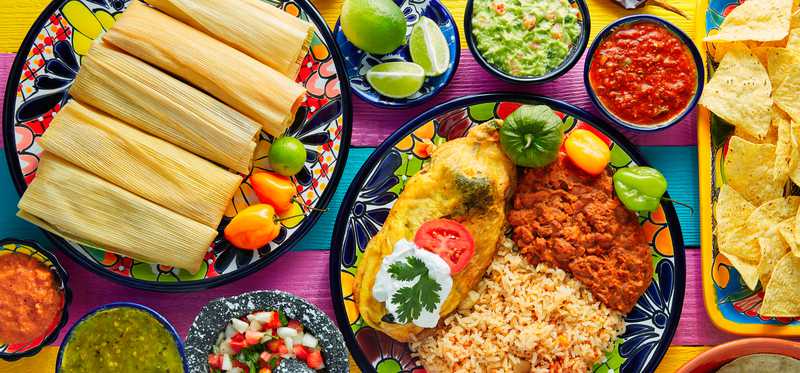 A place setting full of various mexican-style foods.