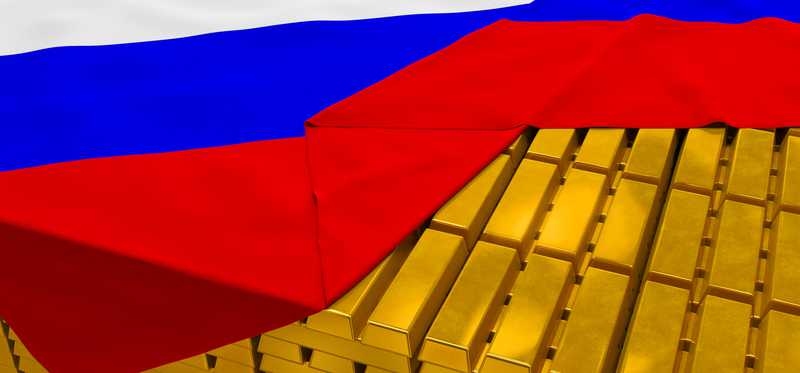 A Russian flag draped over gold bars.