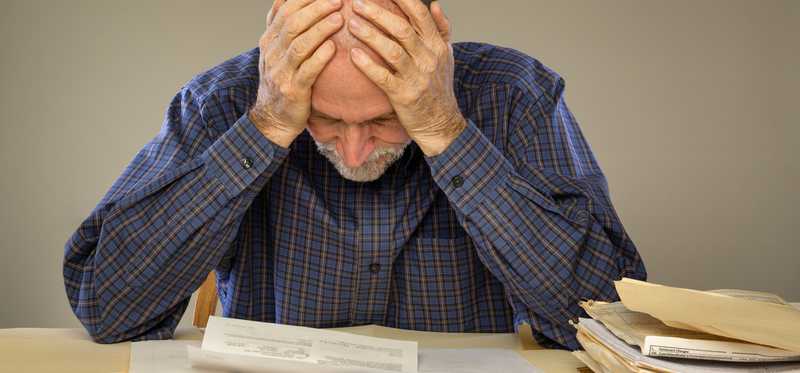 Man with head down and hands to his forehead in frustration.