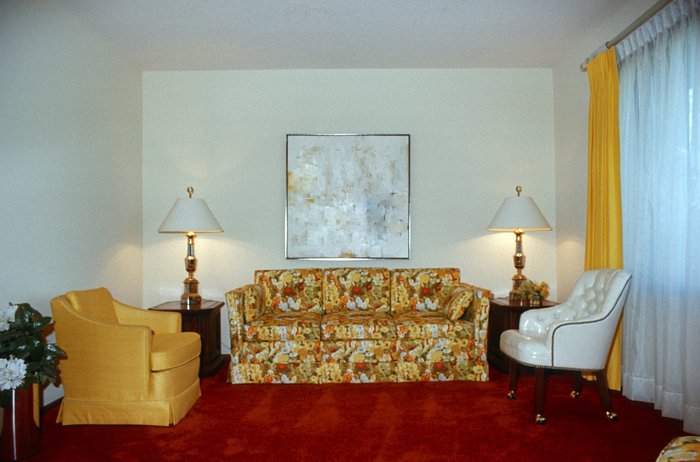 A vintage 1970s living room with gold furniture and red shag rug.