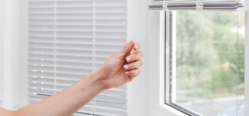 Person pulling the shades down on a window.