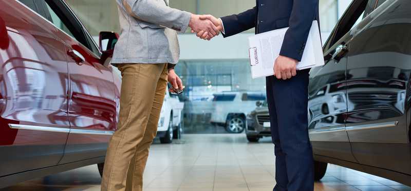 Two men from the legs down in a car showroom.