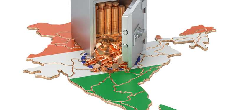 Gold coins falling out of a safe atop a map of India.
