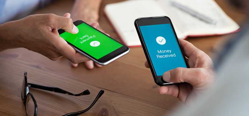 Two people holding cell phones that show money being transferred between them