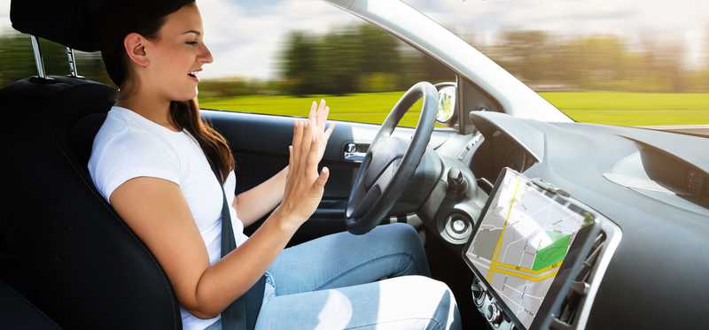 A woman taking her hands off the wheel of a self driving car.