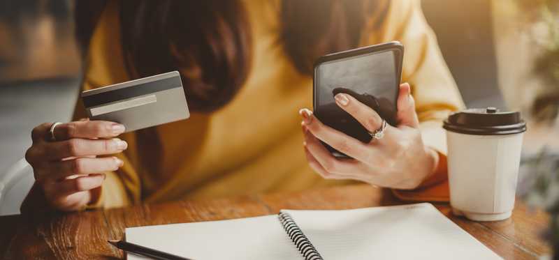 A woman with a cell phone and credit card in her hands