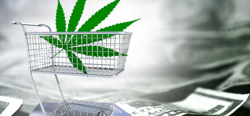 A marijuana leaf in a shopping cart over a credit card and cash.