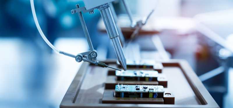 A robotic arm working on a computer board.