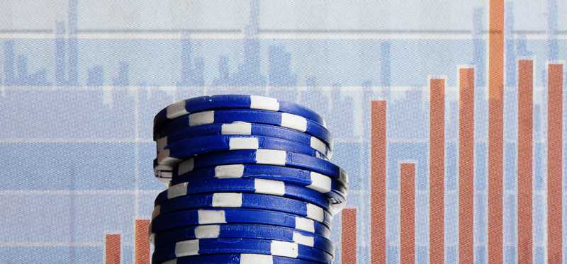 Blue poker chips with investment related imagery in the background