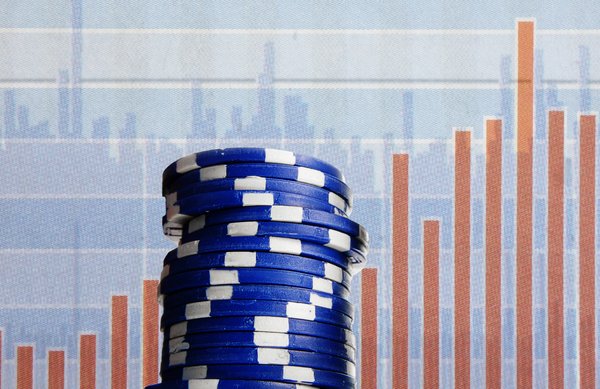 Blue poker chips with investment related imagery in the background