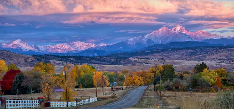 A colorado countryside at sunset with mountains in background.