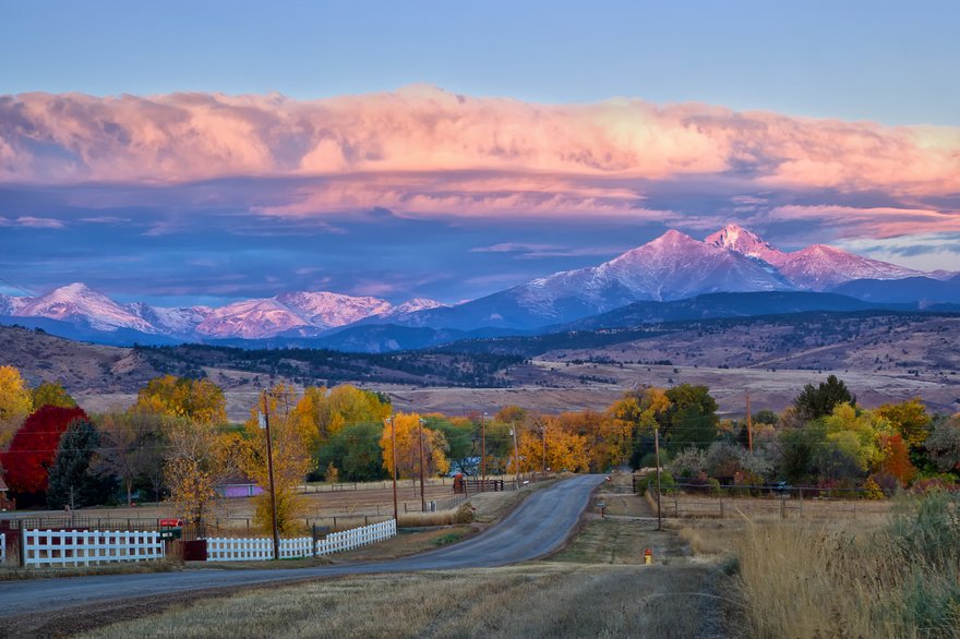 A colorado countryside at sunset with mountains in background.