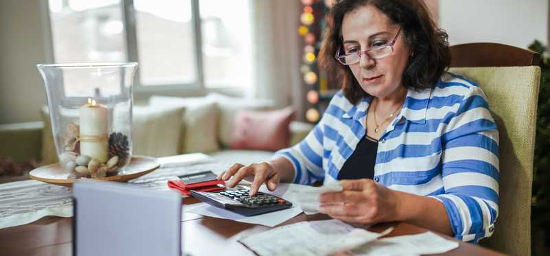 Person sitting at a desk and working on paperwork with a calculator.