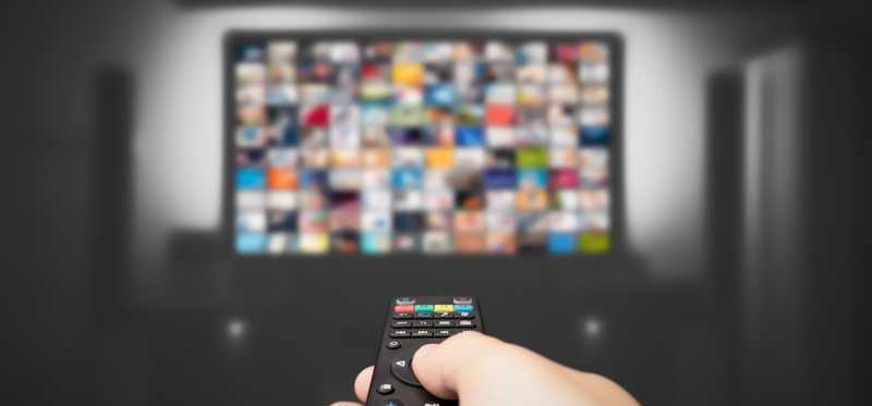 Person holding remote and streaming shows.