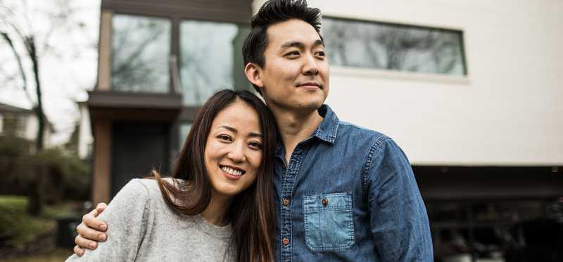 Couple stands in front of contemporary home.