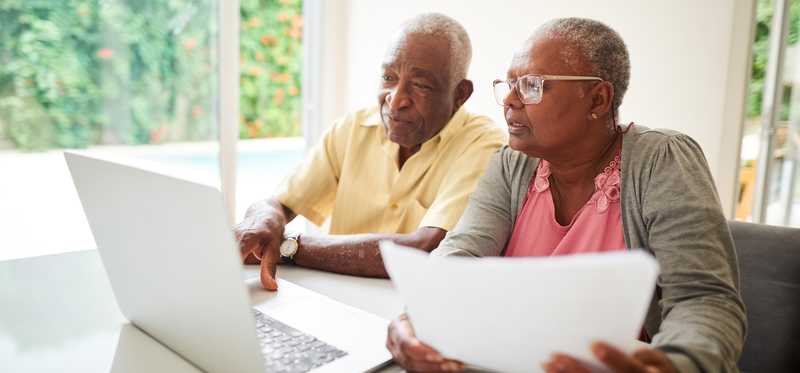 Two people looking at laptop and paperwork.