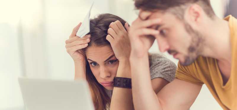 Two stressed out people looking at laptop.