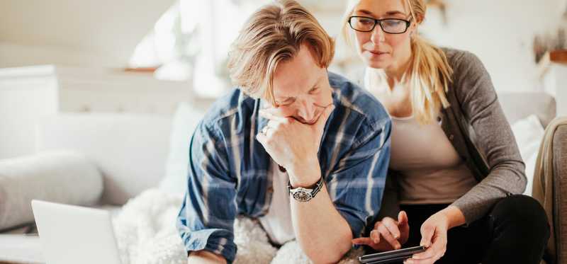 Two people review paperwork on coffee table at home.