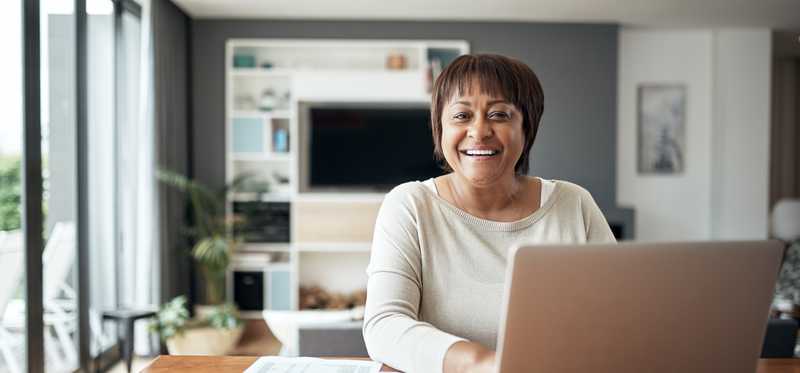 Person smiling while using laptop at desk.