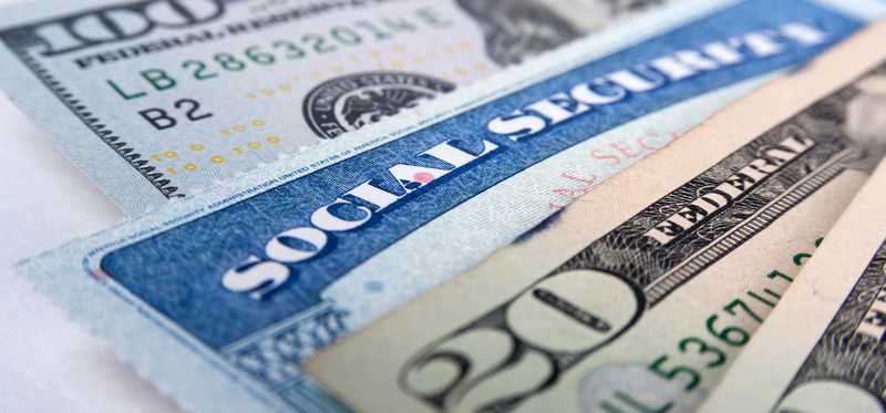 A social security card mixed in with a fan of cash.